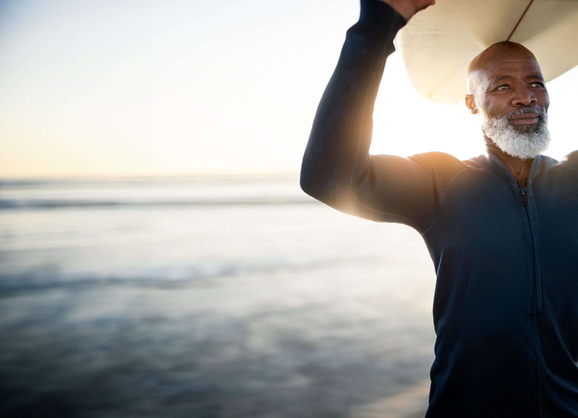 Shot of a mature man carrying a surfboard at the beach