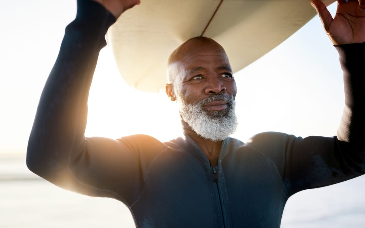 Shot of a mature man carrying a surfboard at the beach